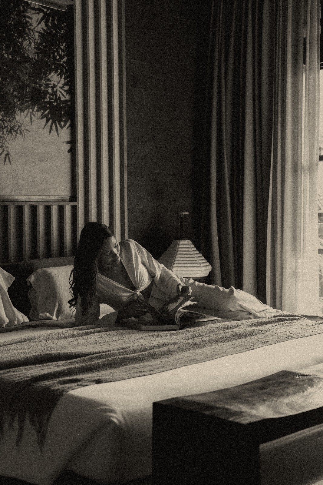 A woman relaxing on her villa bed in a robe
