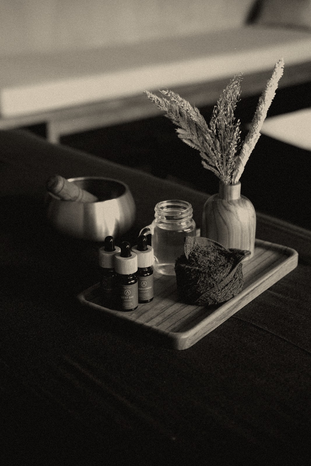 A tray of massage oils, a singing bowl, and dried flowers