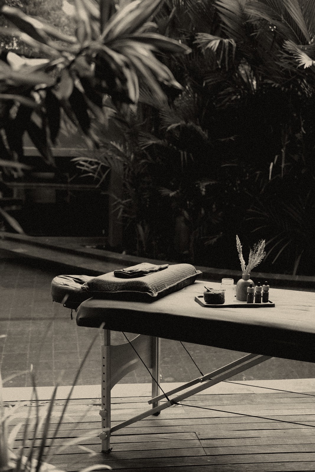 A massage table with towels and a tray of oils set up poolside